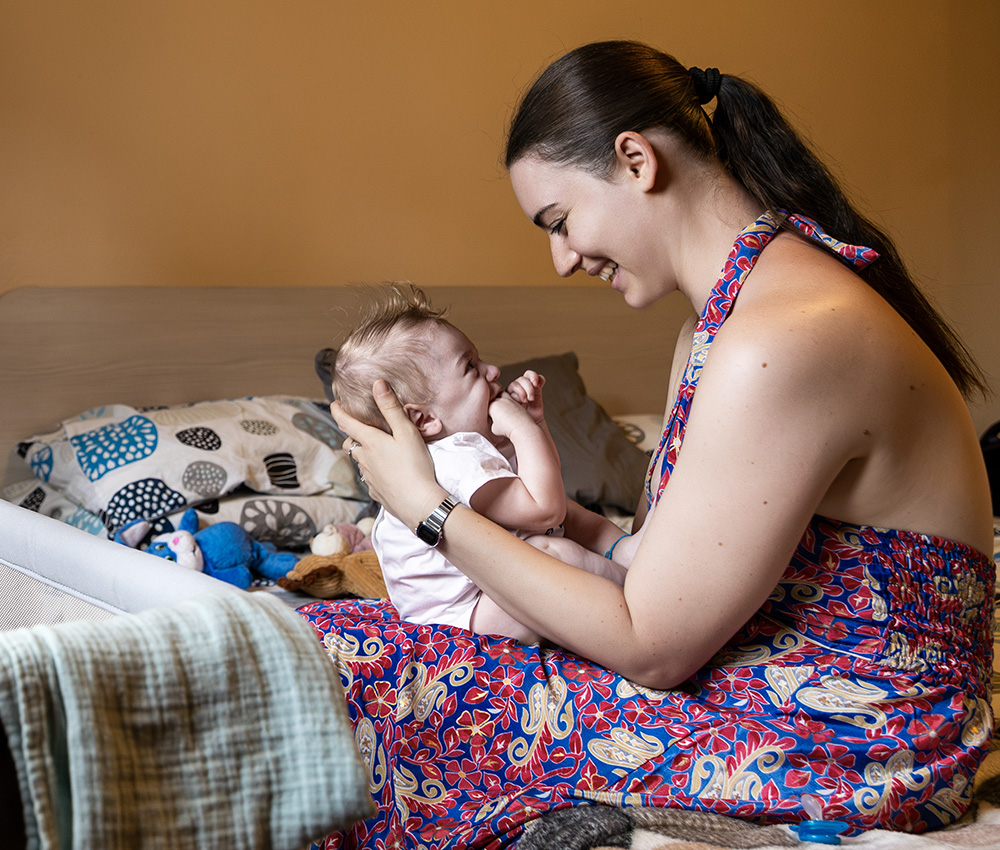 Madre che sorride al neonato sul letto